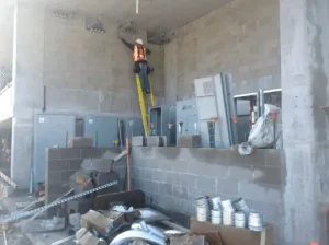 Construction build white brick/concrete look with man on ladder installing wiring.