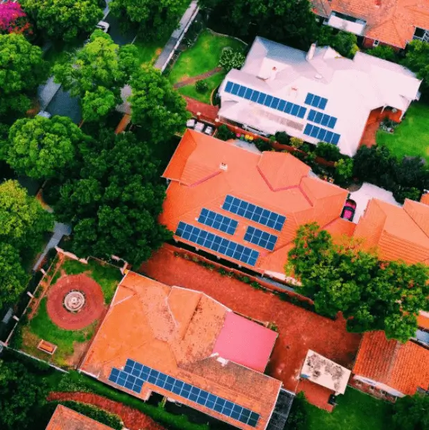 Overhead view of 4 orange roofed houses with solar panels scattered on them