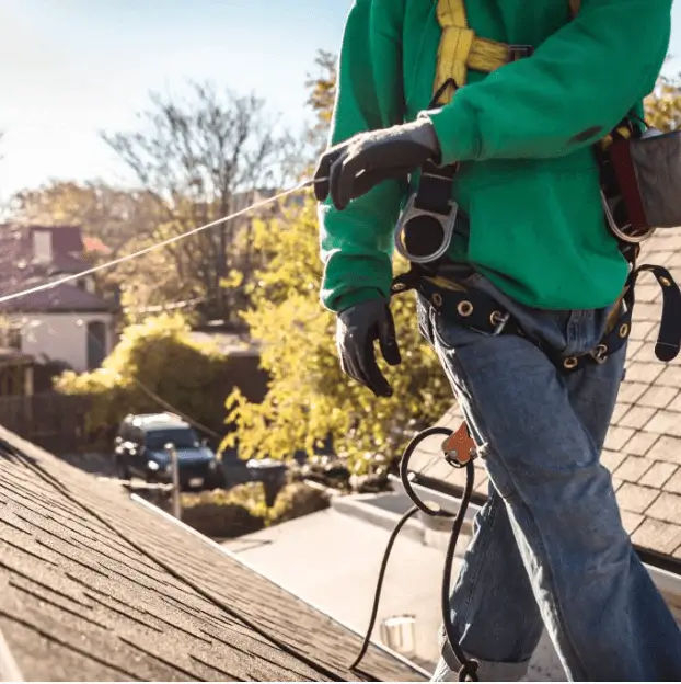 Person walking on rood in green sweatshirt holding measuring wire