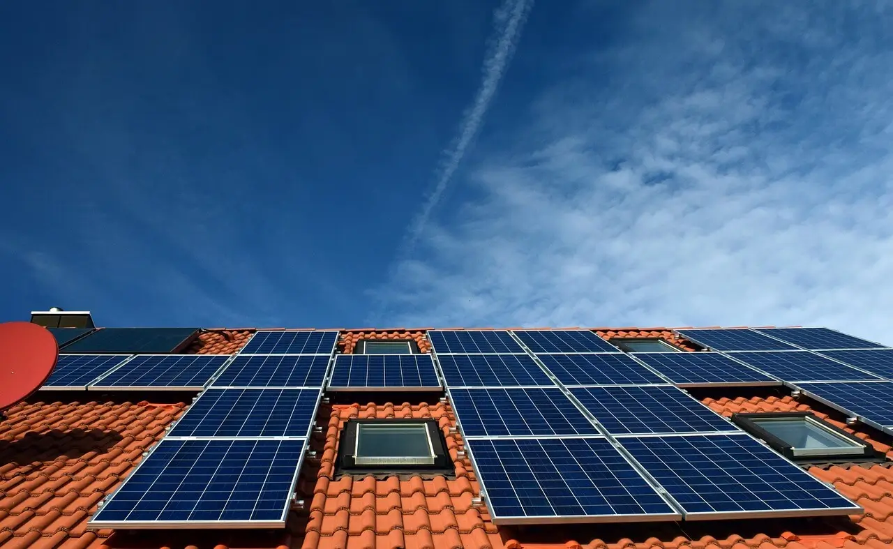 Orange roof with scattered solar panels installed and blue sky above