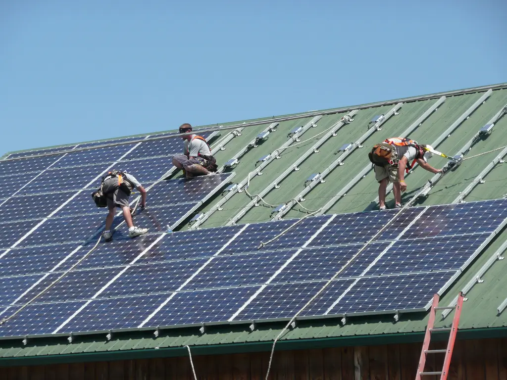 People on a roof replacing solar panels due to hail damage