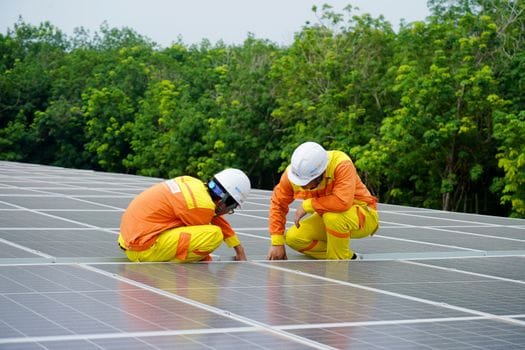 solar installation team working on solar panels with trees in the background.